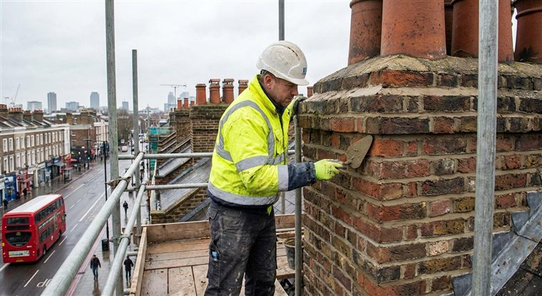 Roofers working on a chimney stack on a London terrace